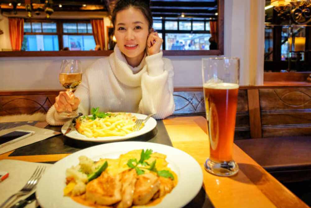 Woman in a chinese restaurant eating chinese dish and having wine